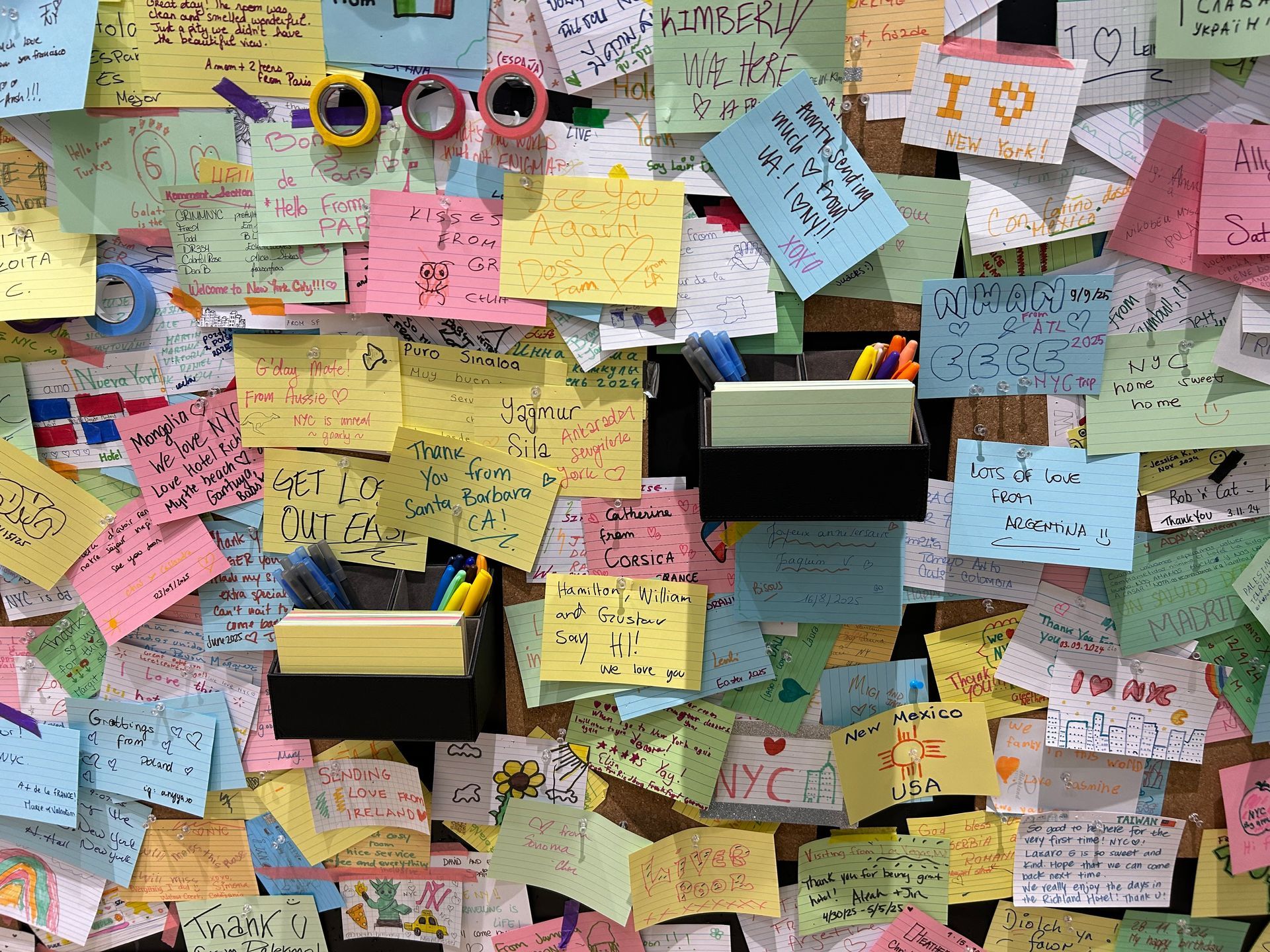 Corkboard covered in colorful sticky notes; some with handwritten messages.