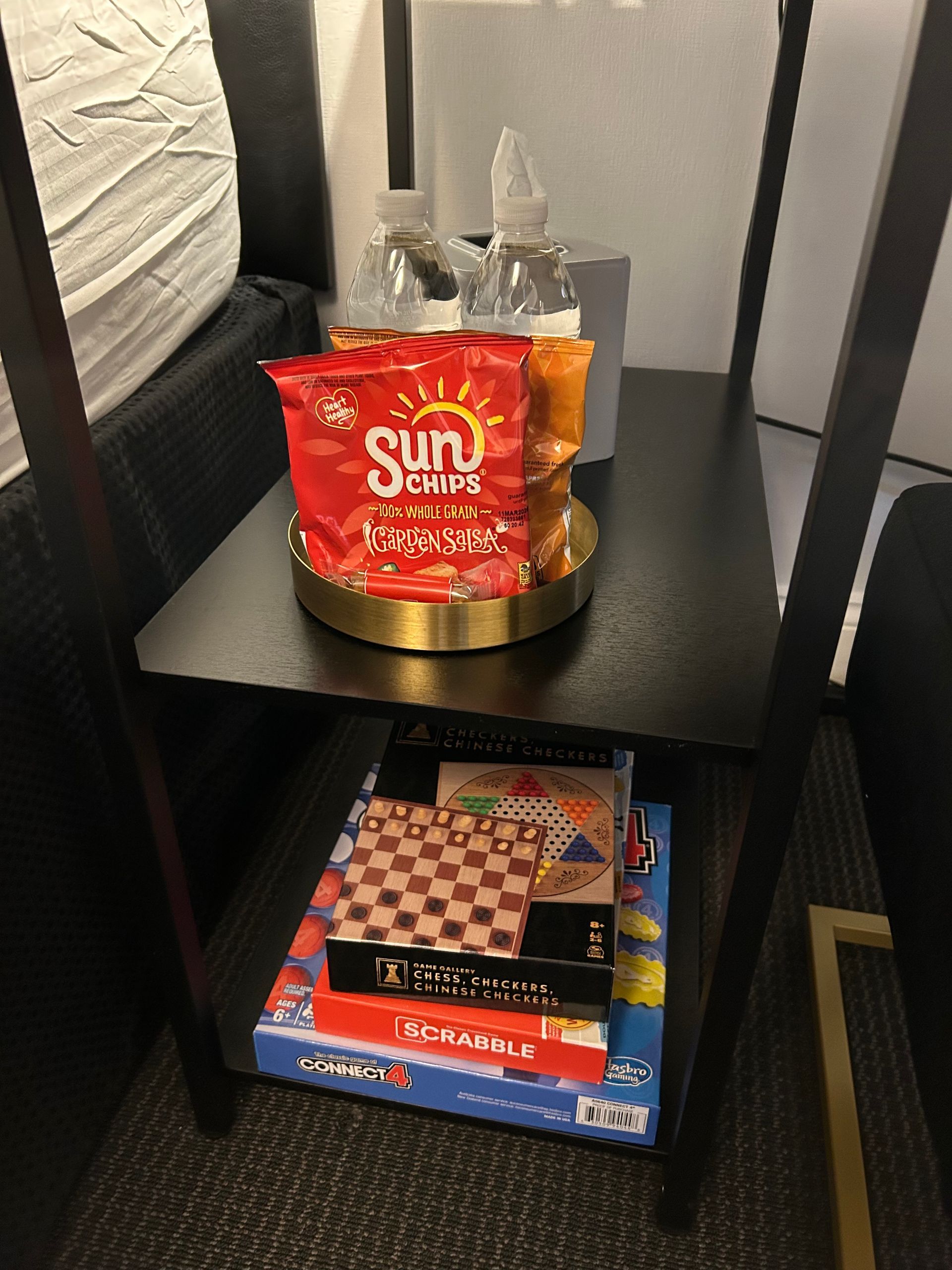 Black shelf with snacks, games, and decorative bottles.