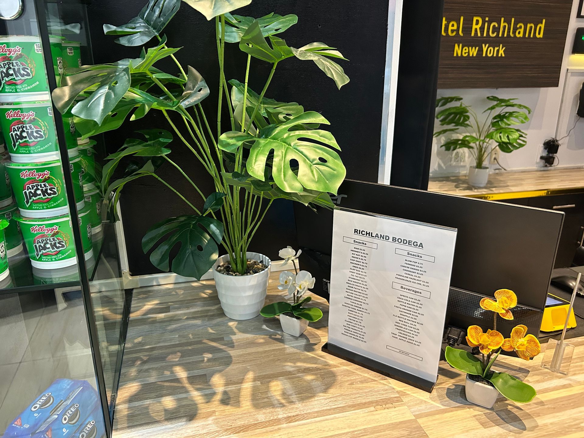 A plant and sign on a counter next to instant noodles. 