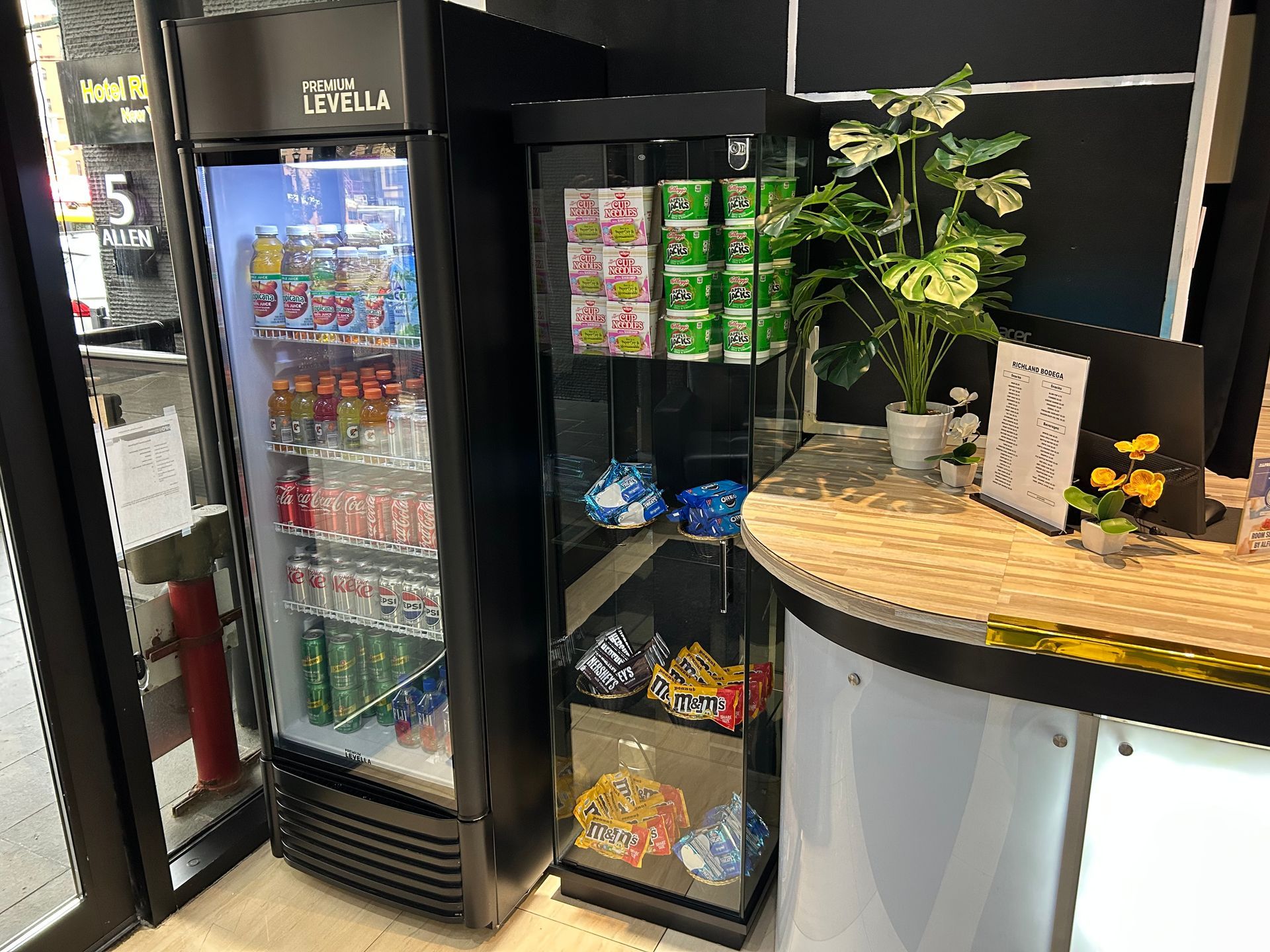 A beverage cooler and display case with drinks and snacks at a checkout counter.