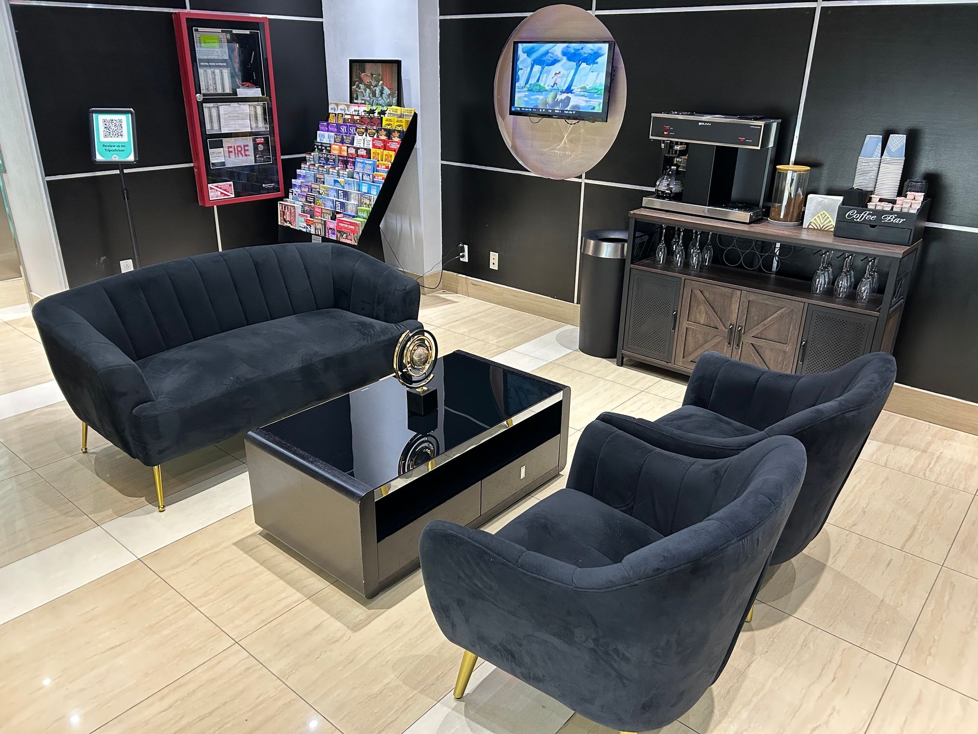 Lounge area with black furniture, coffee station, and reading material.