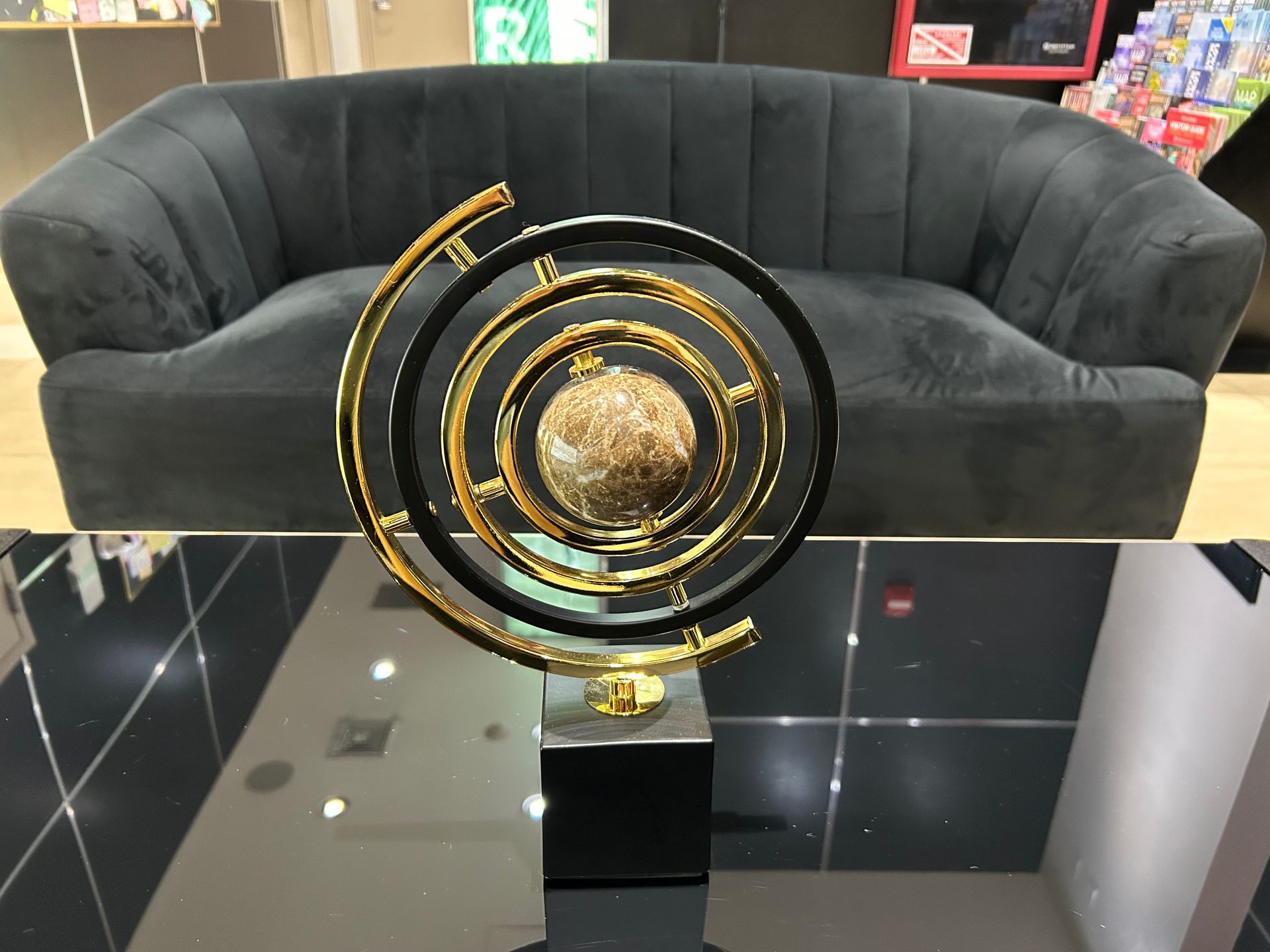 Ornament on a black table in front of a dark gray sofa; golden and black swirl design.