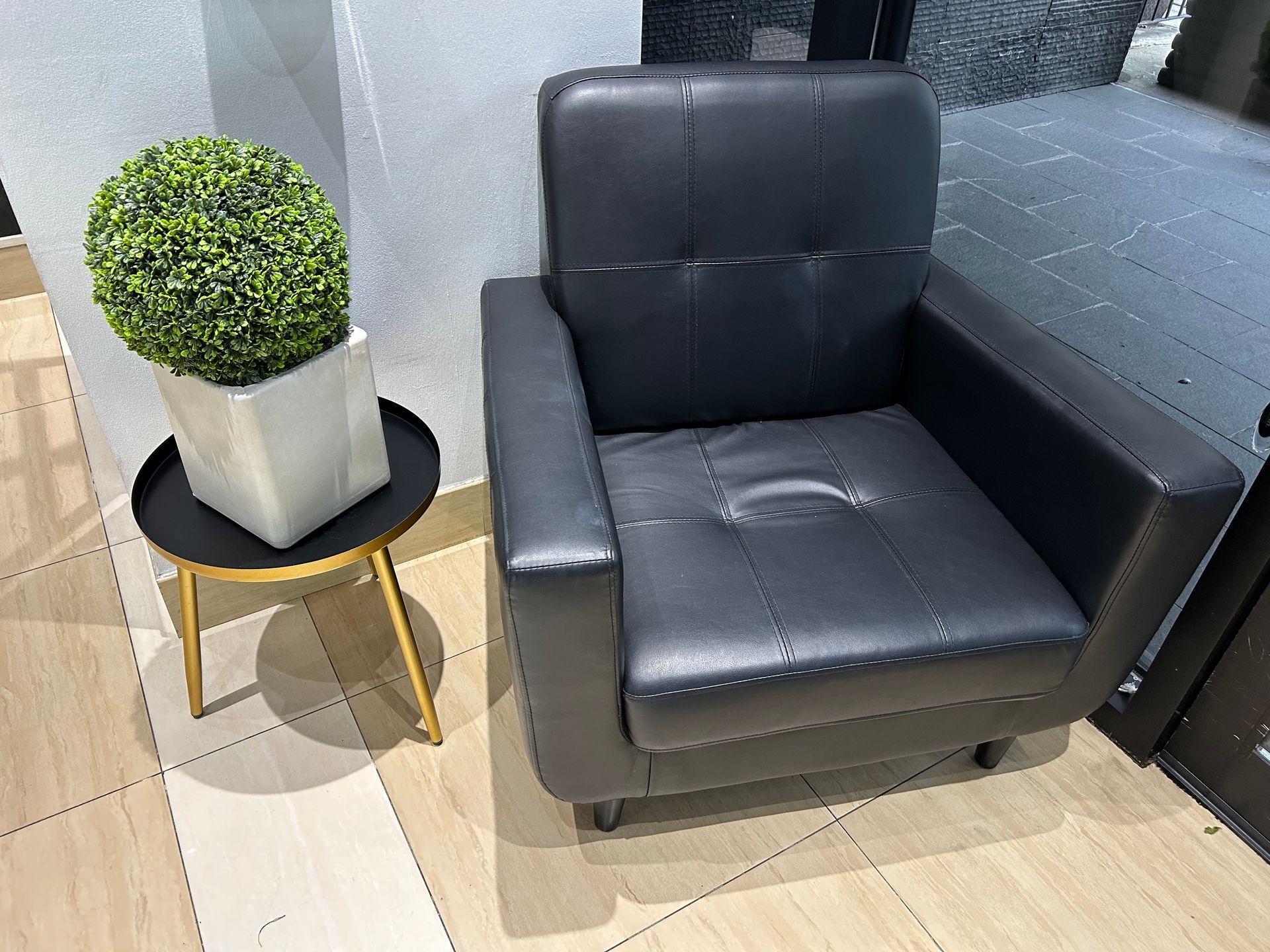 Black leather armchair next to a small table with a potted plant.