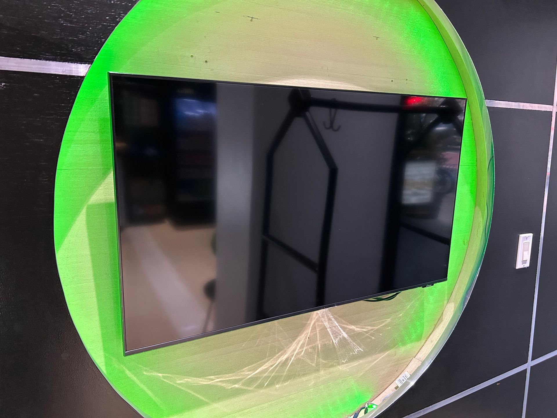 Black screen reflecting a room, inside of a green circle on a dark background.