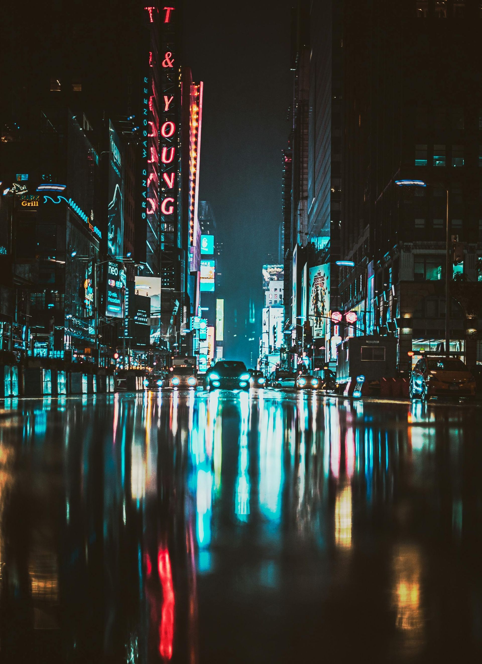 City street at night reflecting bright neon lights in puddles.