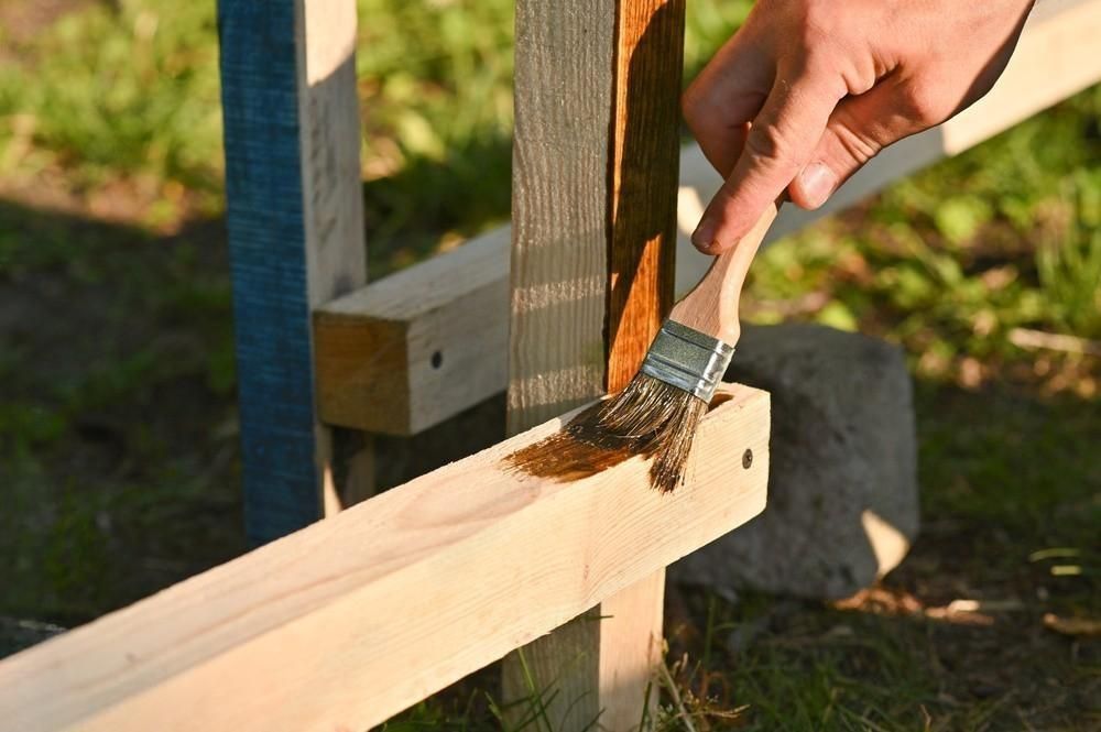 a person is painting a wooden post with a brush .