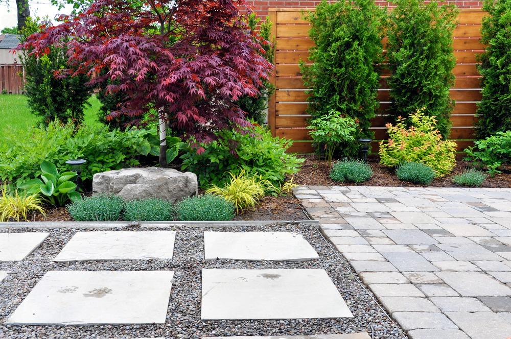 a patio with a stone walkway and a wooden fence in the background .