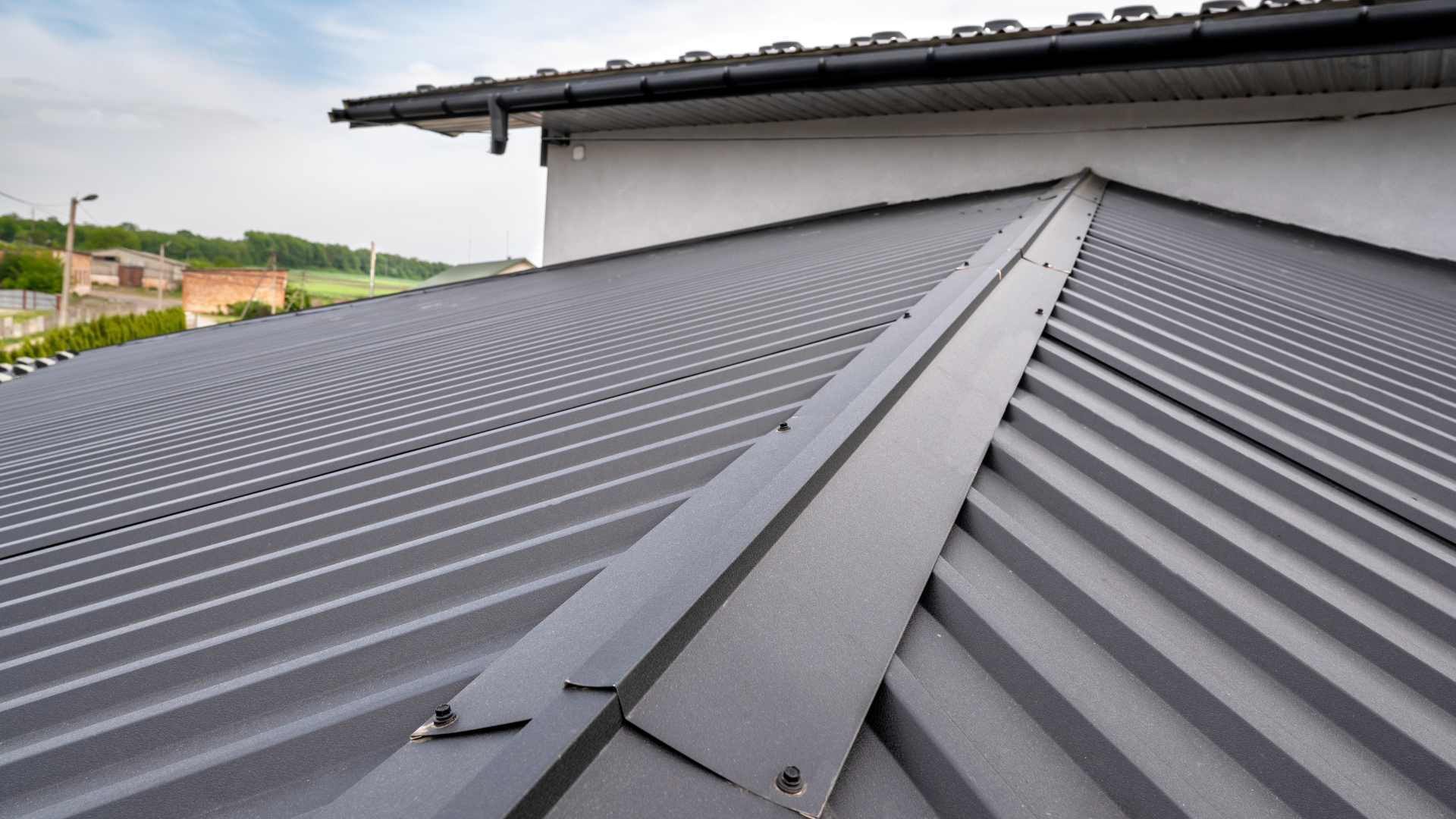 Gray metal roof with ridges, angled edge, and small fasteners.