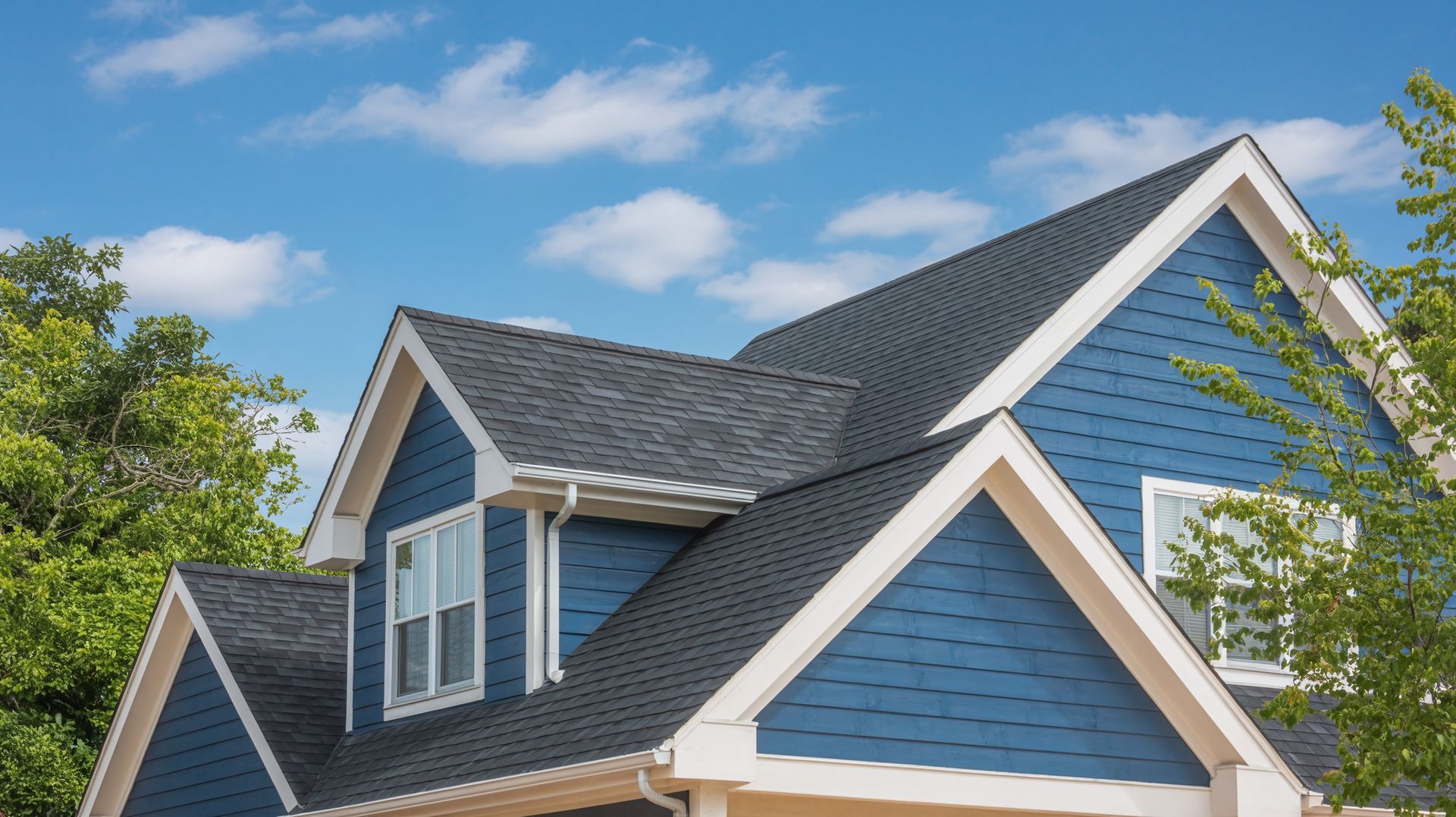 Blue house with dark gray roof against a blue sky, partial view.