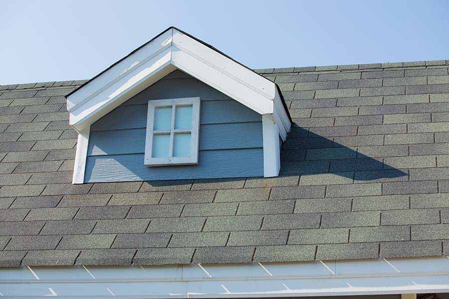 Black rain gutters along a terracotta tile roof, against a cloudy sky.