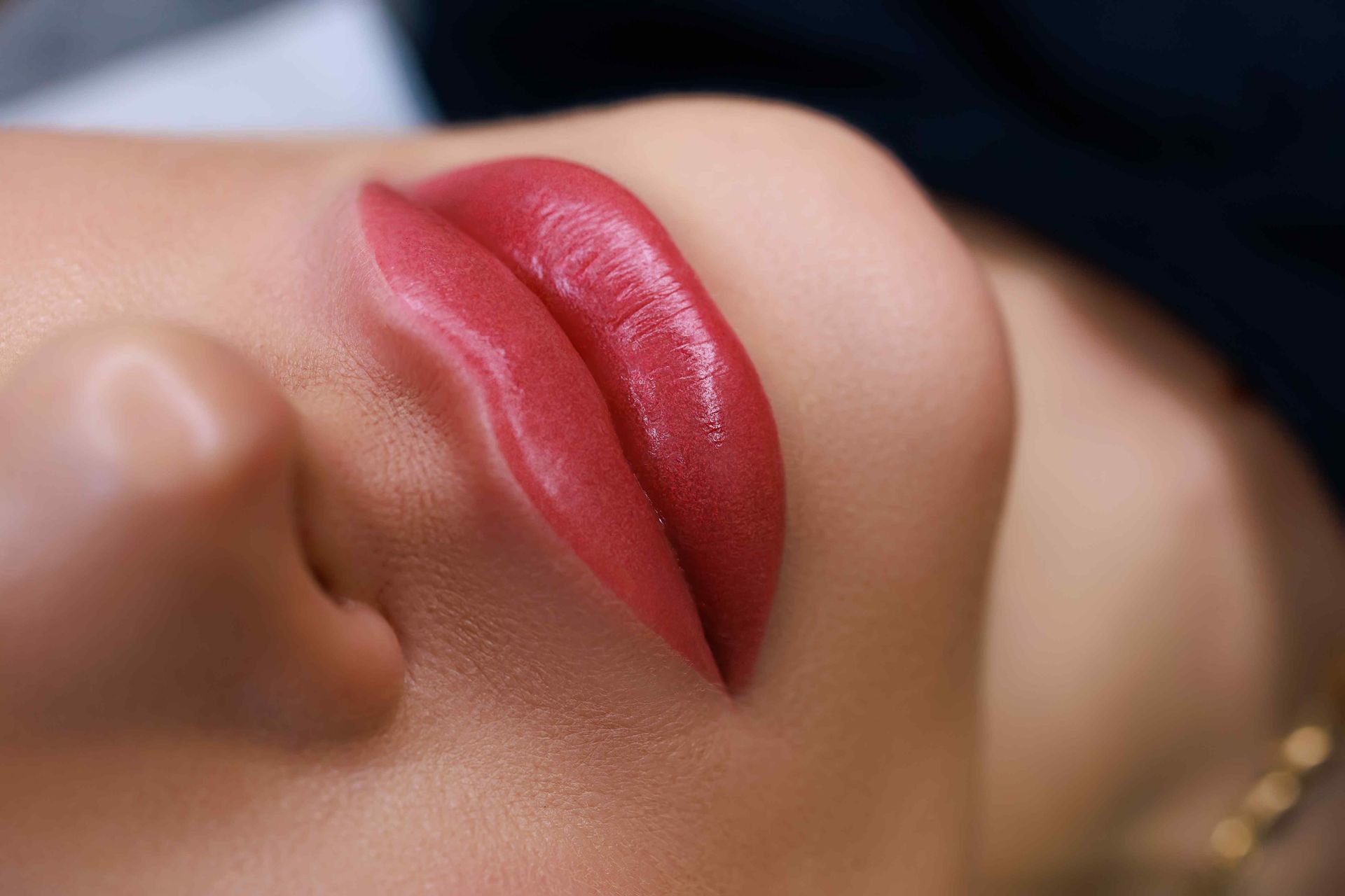 Woman receiving lip cosmetic treatment. Technician holding device, wearing gloves, indoors.