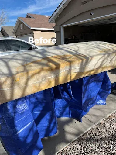 Before photo: stained mattress covered by a blue tarp, outside a garage on a sunny day.