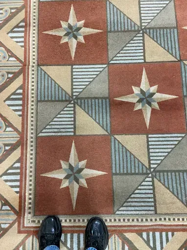 Black shoes on patterned tile floor featuring starbursts and geometric shapes in muted colors.