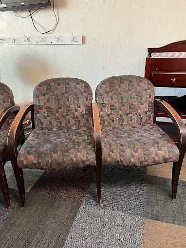Two upholstered chairs with wood arms and patterned fabric in a room with a neutral carpet.