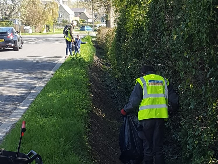 Volunteers in Hi-vis vests clearing litter from the roadside