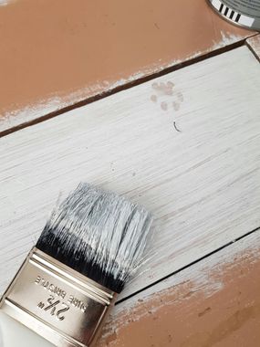 A close up of a paint brush on a wooden surface.