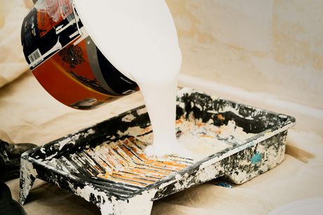 A person is pouring paint into a paint tray