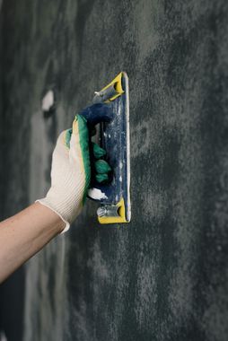 A person is plastering a wall with a trowel.