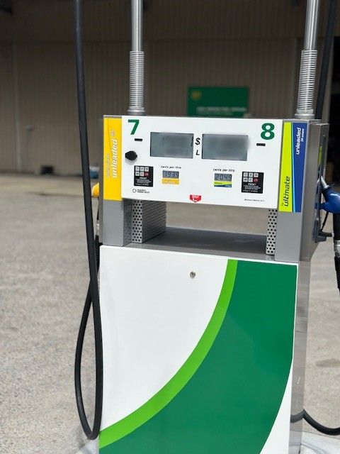 Gas pump at a BP station. White, green, and yellow design with digital displays showing fuel prices and gallons.