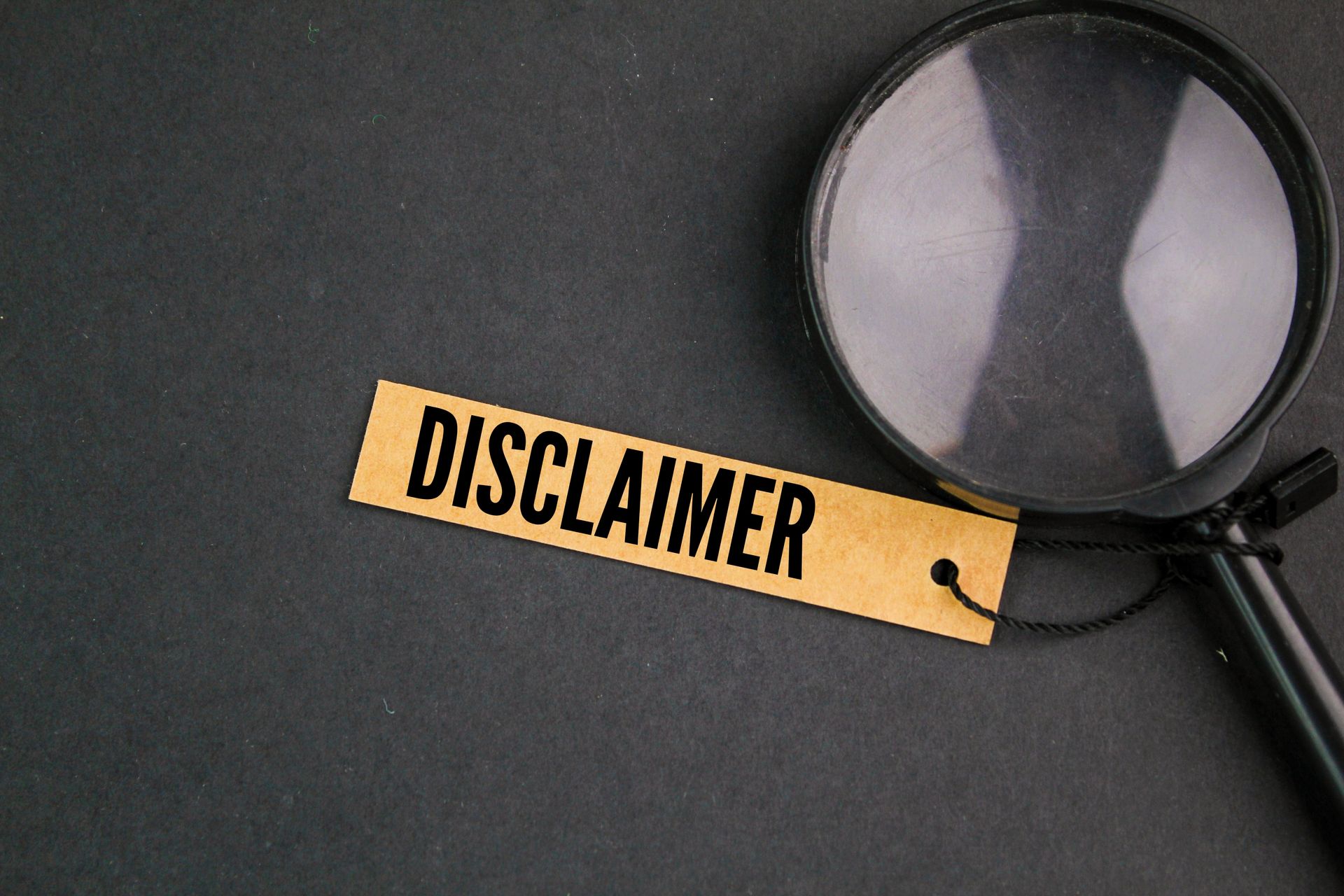 A magnifying glass is sitting next to a tag that says disclaimer