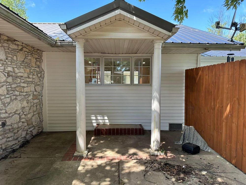 The front of a house with a porch and a wooden fence.