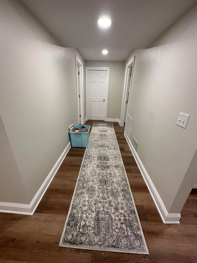 A long hallway with hardwood floors and a rug on the floor.