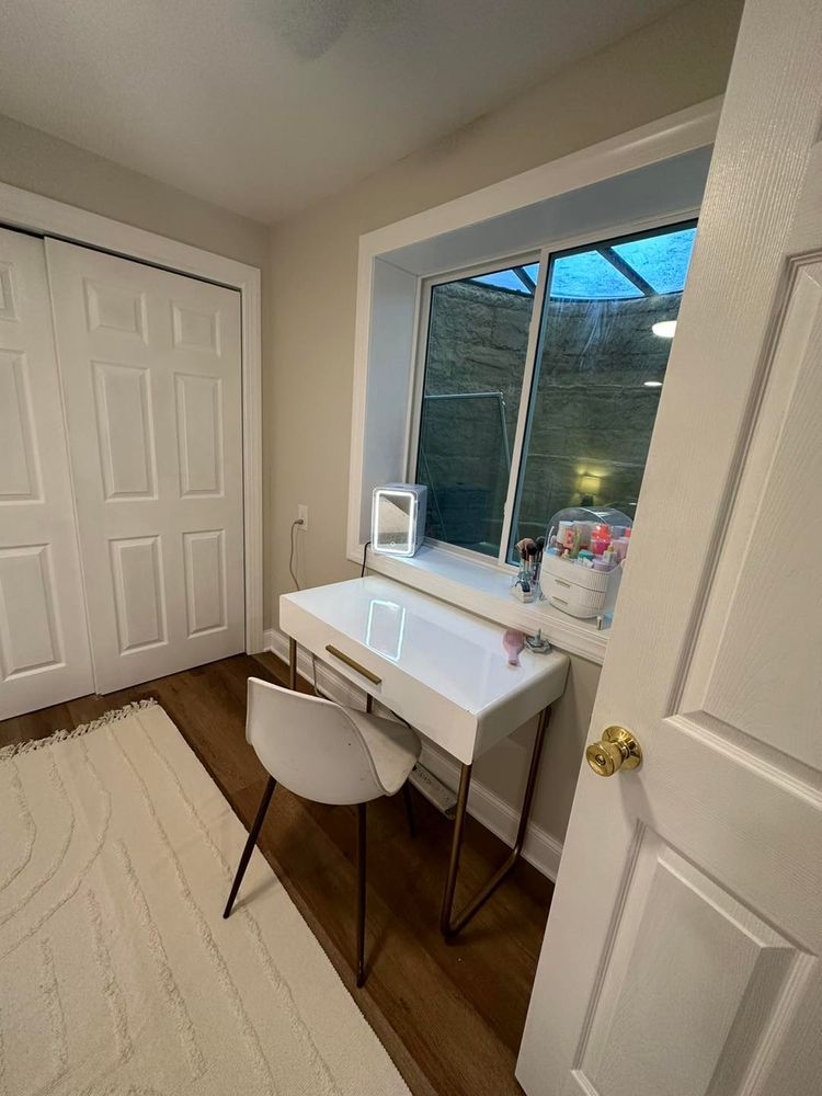 A room with a desk and chair in front of a window.