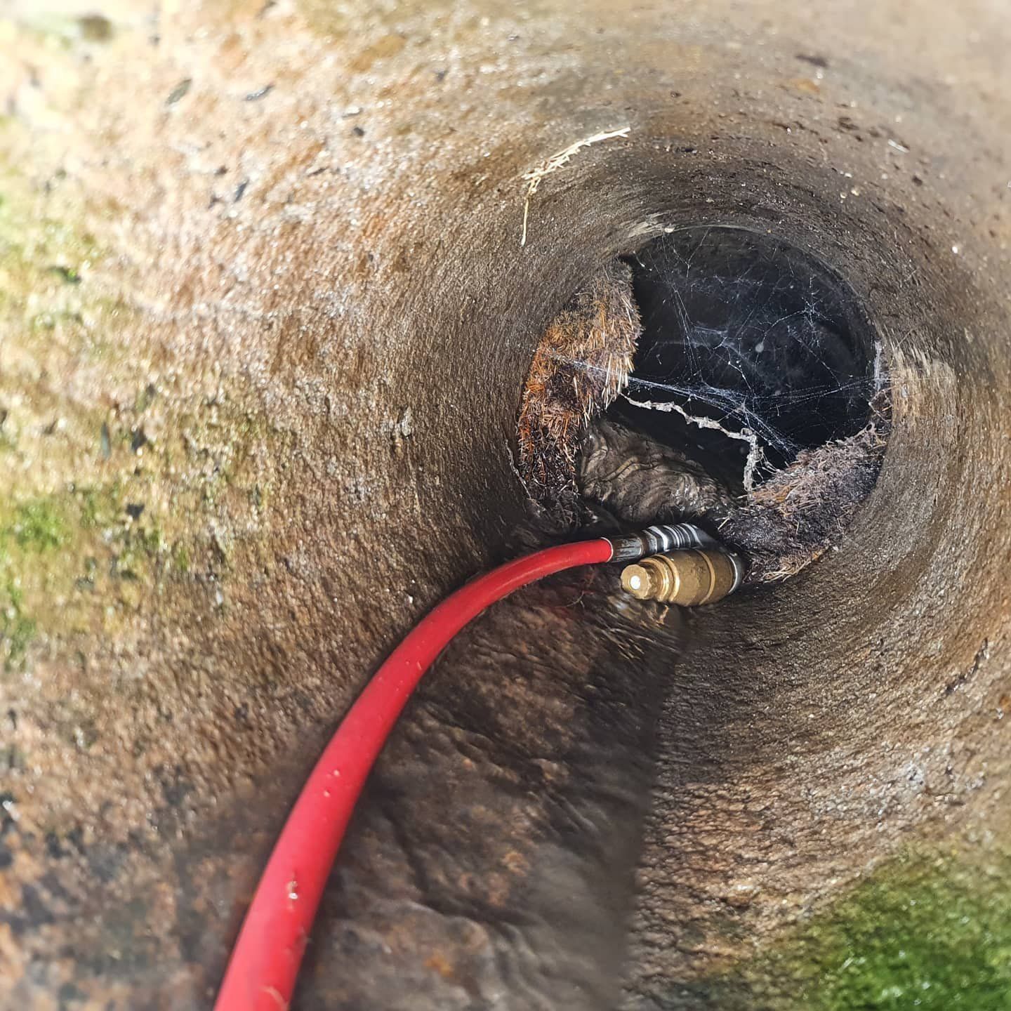A red hose is connected to a hole in the ground
