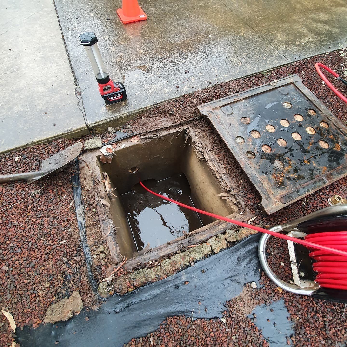 A manhole cover with a red cable coming out of it.