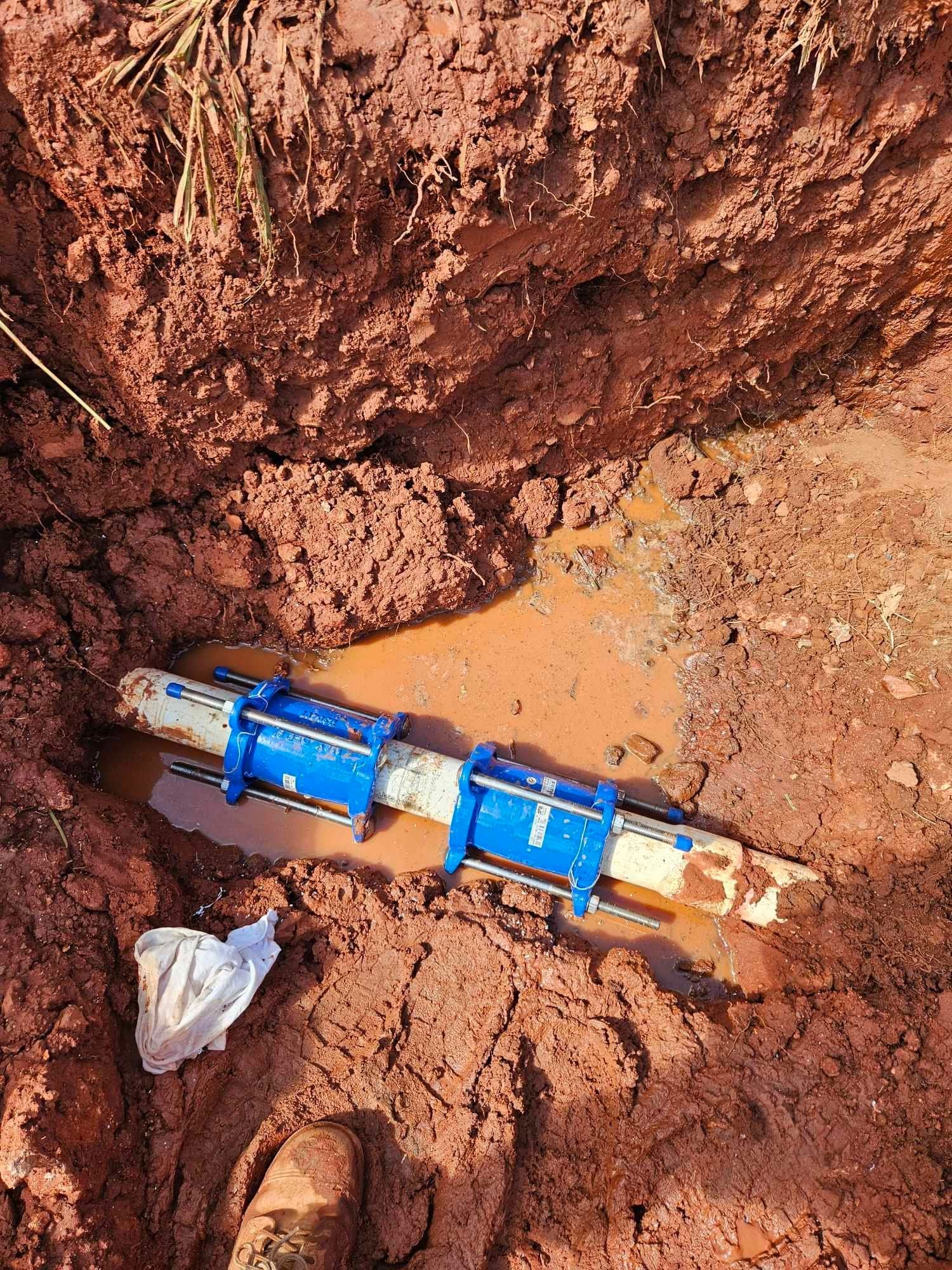A blue pipe is laying in the dirt.