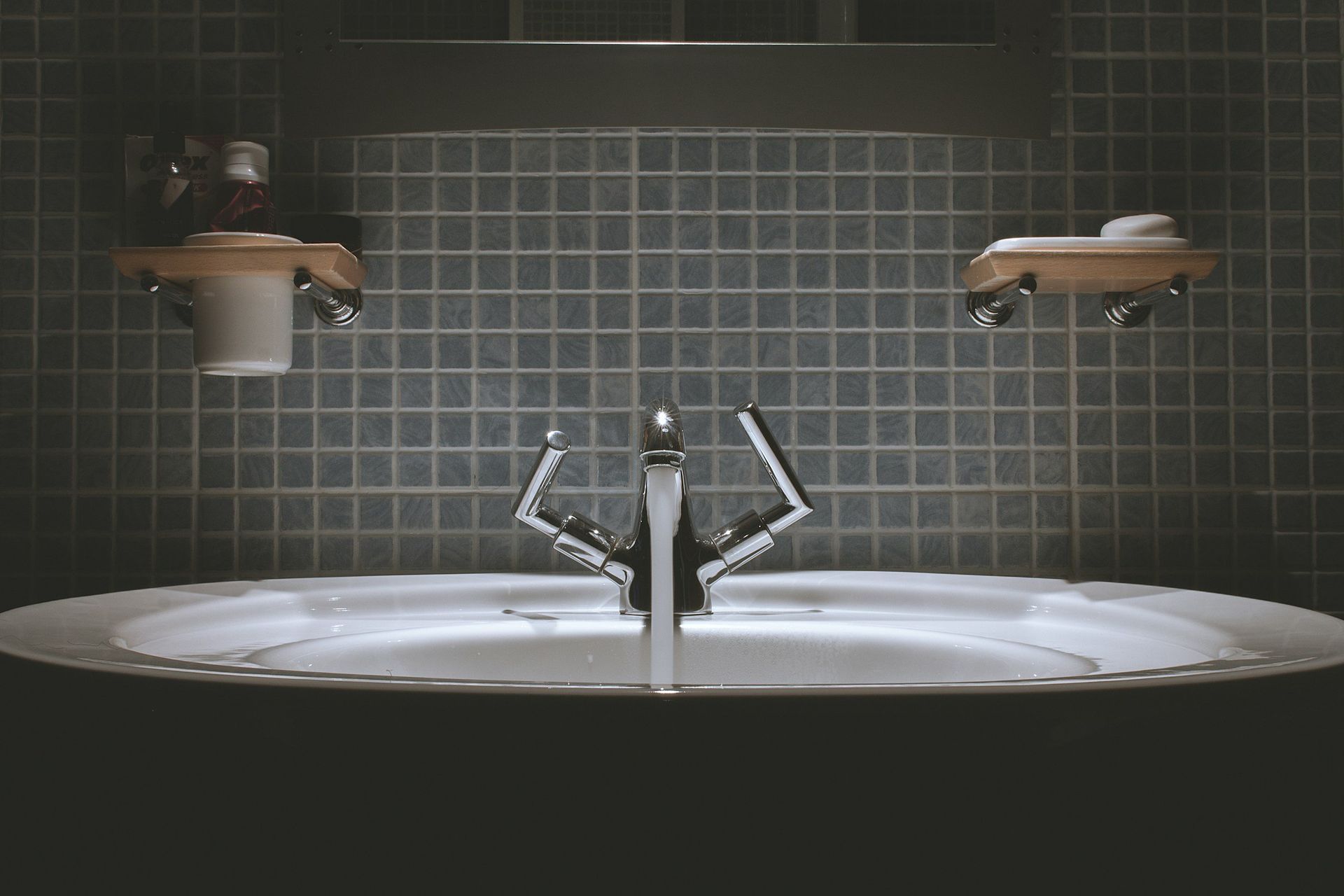A bathroom sink with a faucet and two shelves.