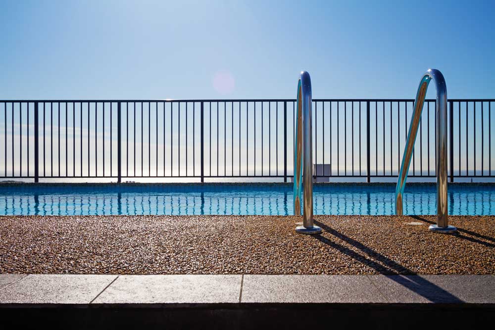 Swimming Pool Edge With Ladder And Sky Background — Pool Maintenance in Bowen, QLD