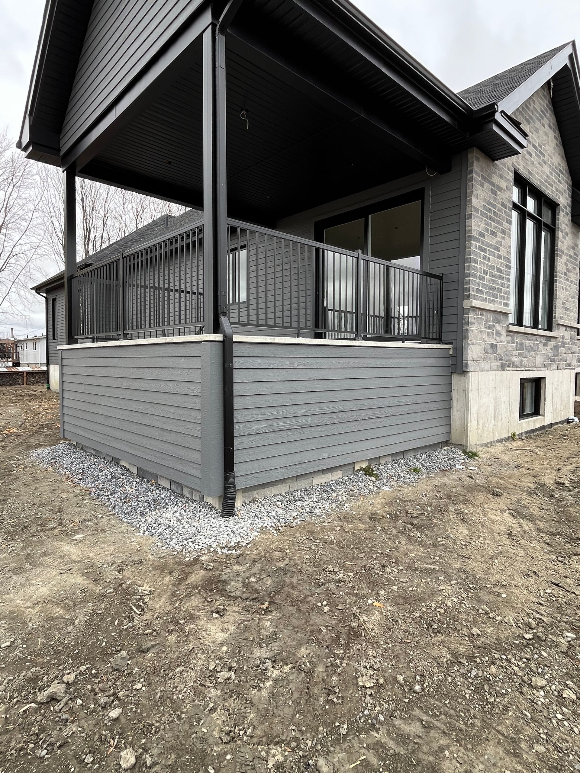 Une maison avec un grand porche et une balustrade noire.