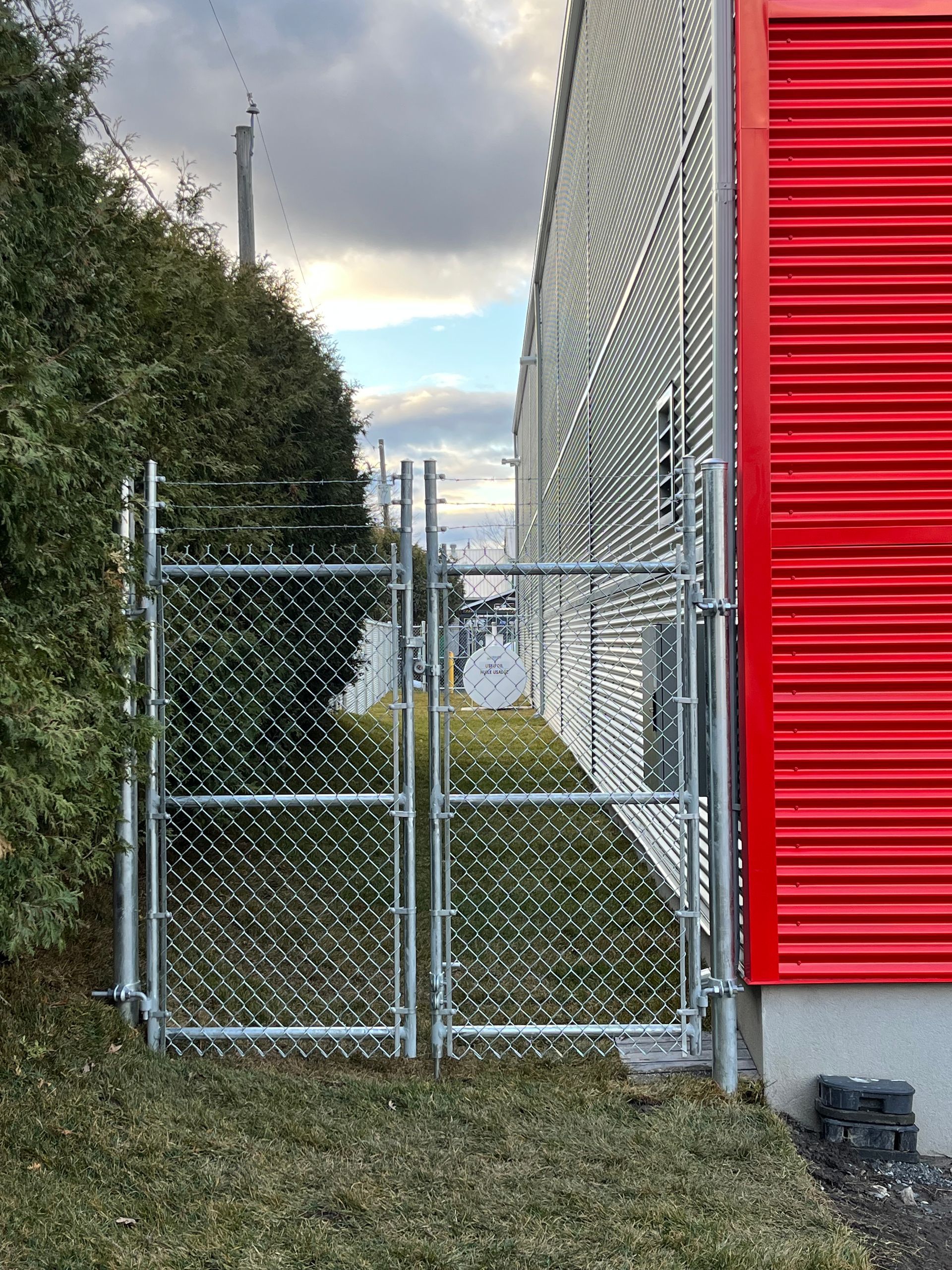 Une clôture grillagée se trouve à côté d'un bâtiment rouge.