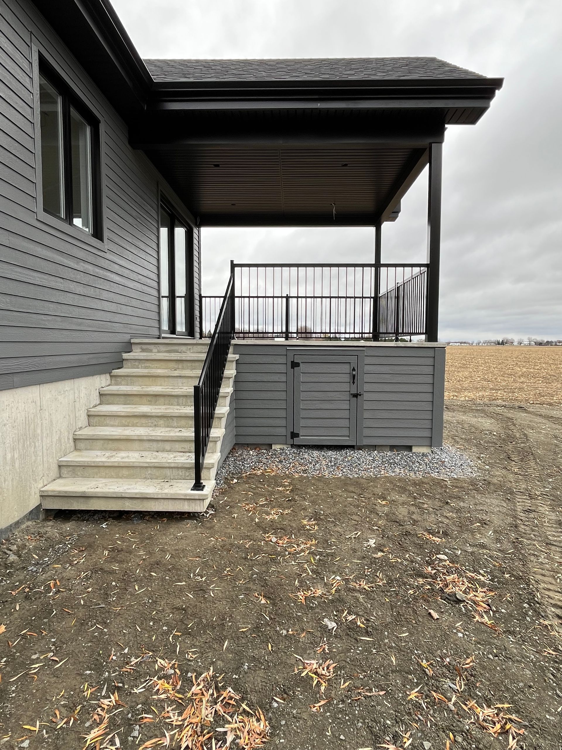 Une maison noire avec un porche et des escaliers qui y mènent.