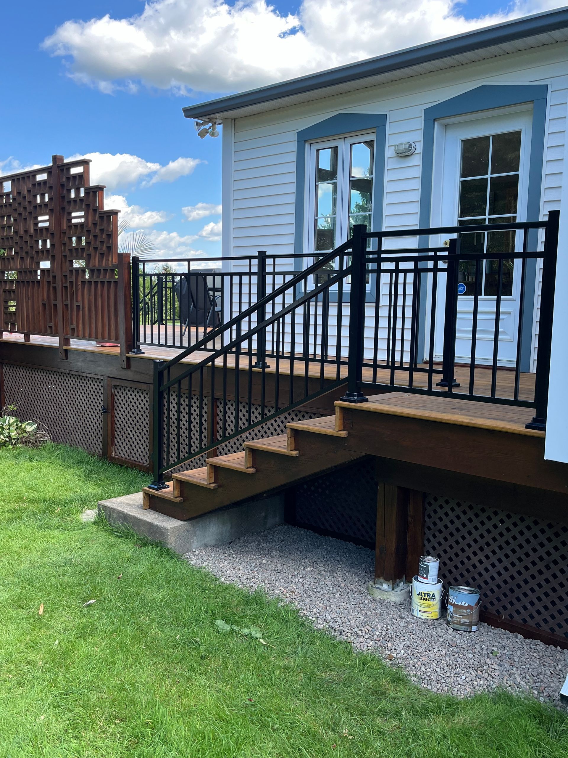 Une maison blanche avec une terrasse en bois et des escaliers qui y mènent.