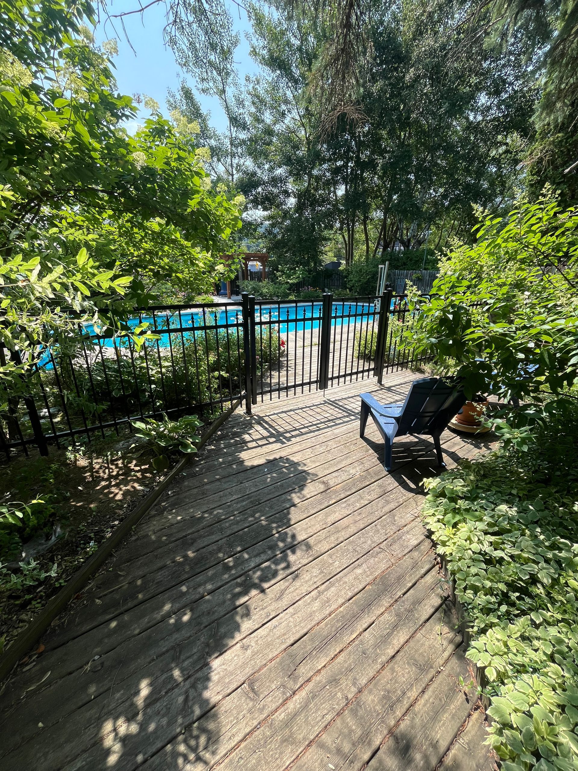 Une chaise est assise sur une terrasse en bois à côté d'une piscine.