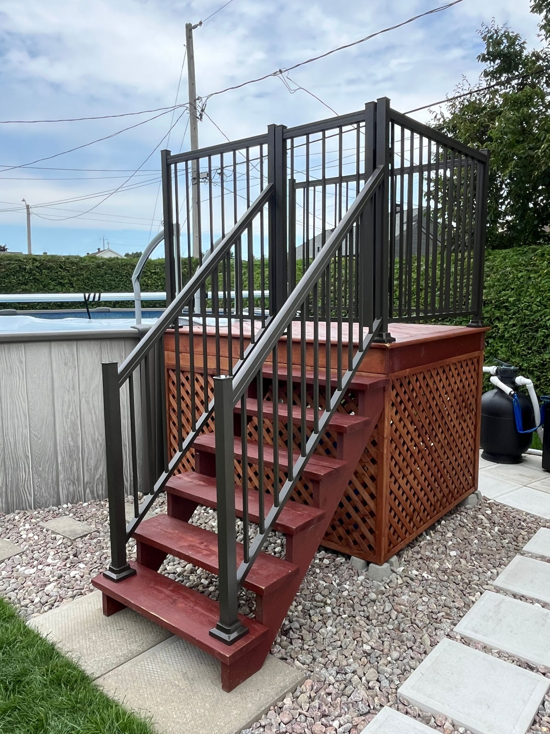 Une terrasse en bois avec des escaliers qui y mènent à côté d'une piscine.