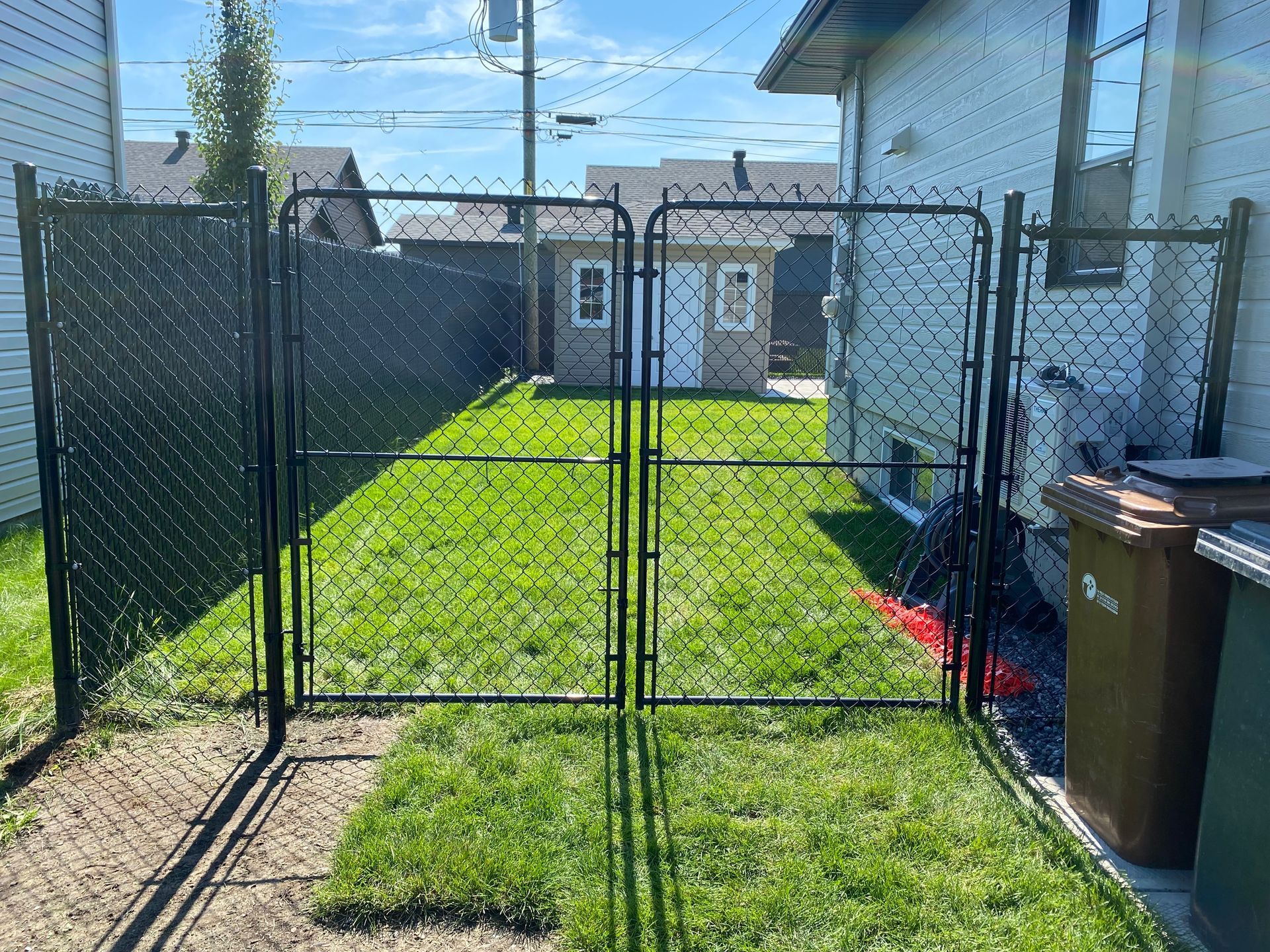 Une cour arrière avec une clôture grillagée et un portail.