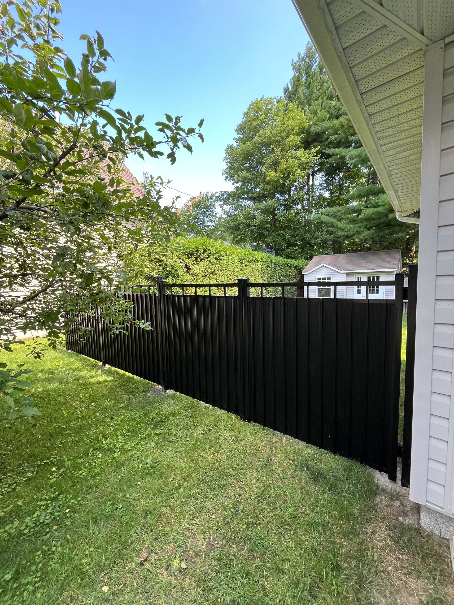 Une clôture noire se trouve à côté d'une maison blanche.