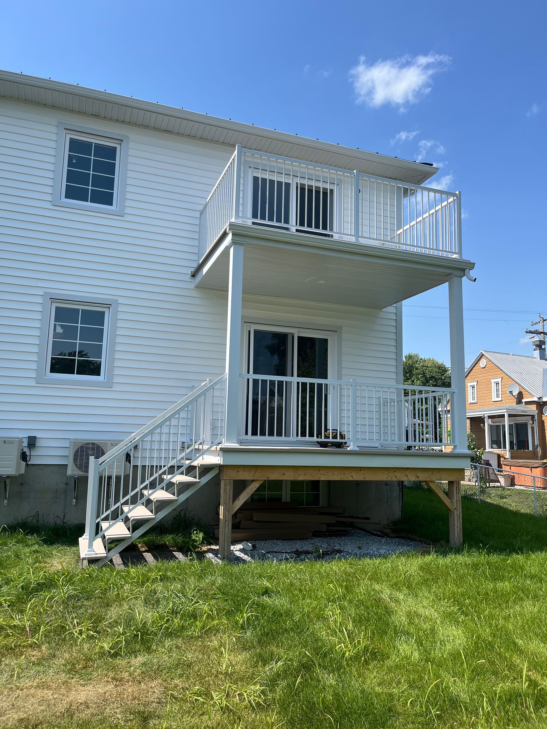 L'arrière d'une maison blanche avec une terrasse et des escaliers.