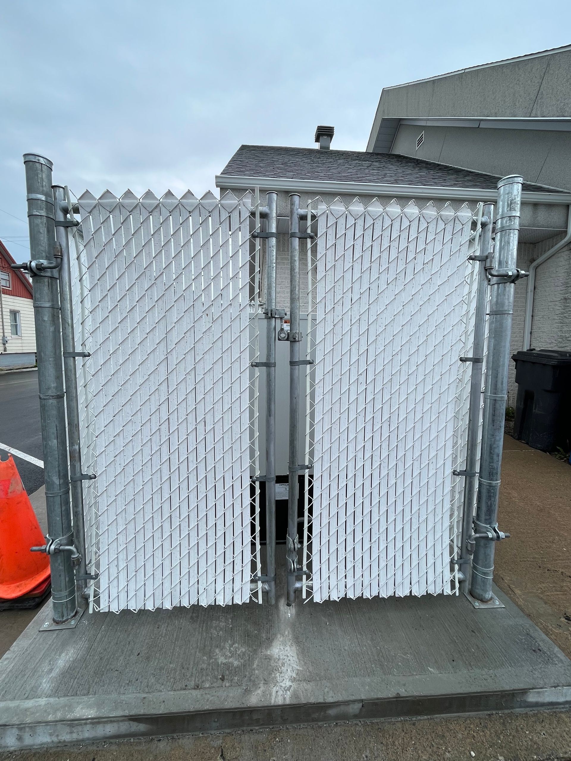 Une clôture grillagée avec des lattes blanches entoure un bâtiment.