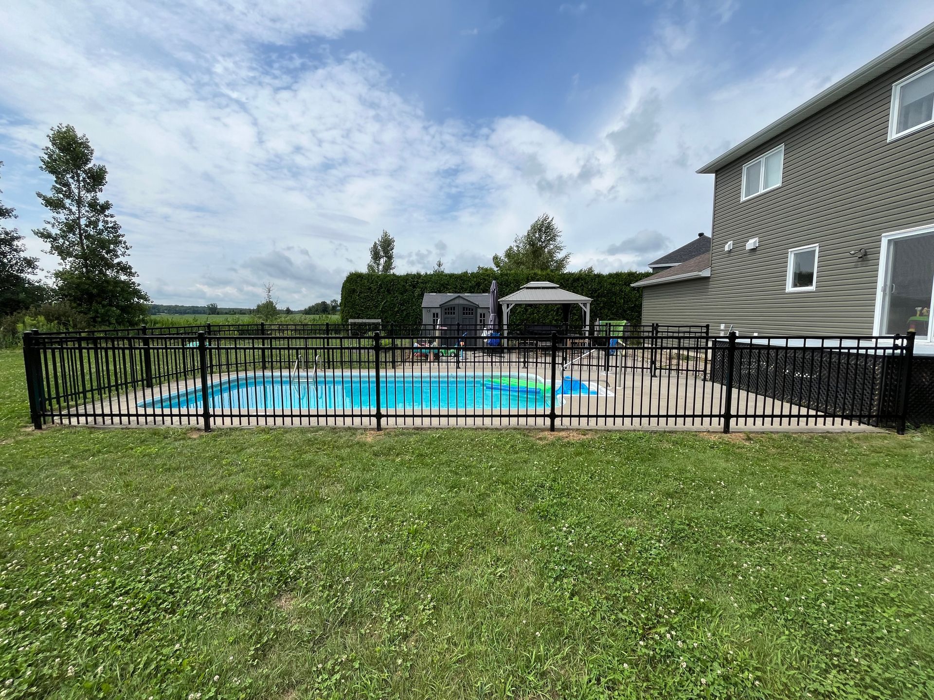 Une grande piscine entourée d'une clôture dans une cour arrière.