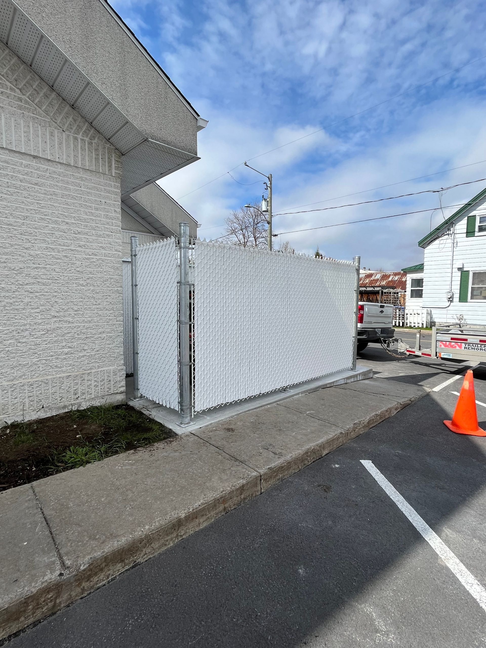 Une clôture blanche se trouve sur le côté de la route à côté d'un bâtiment.