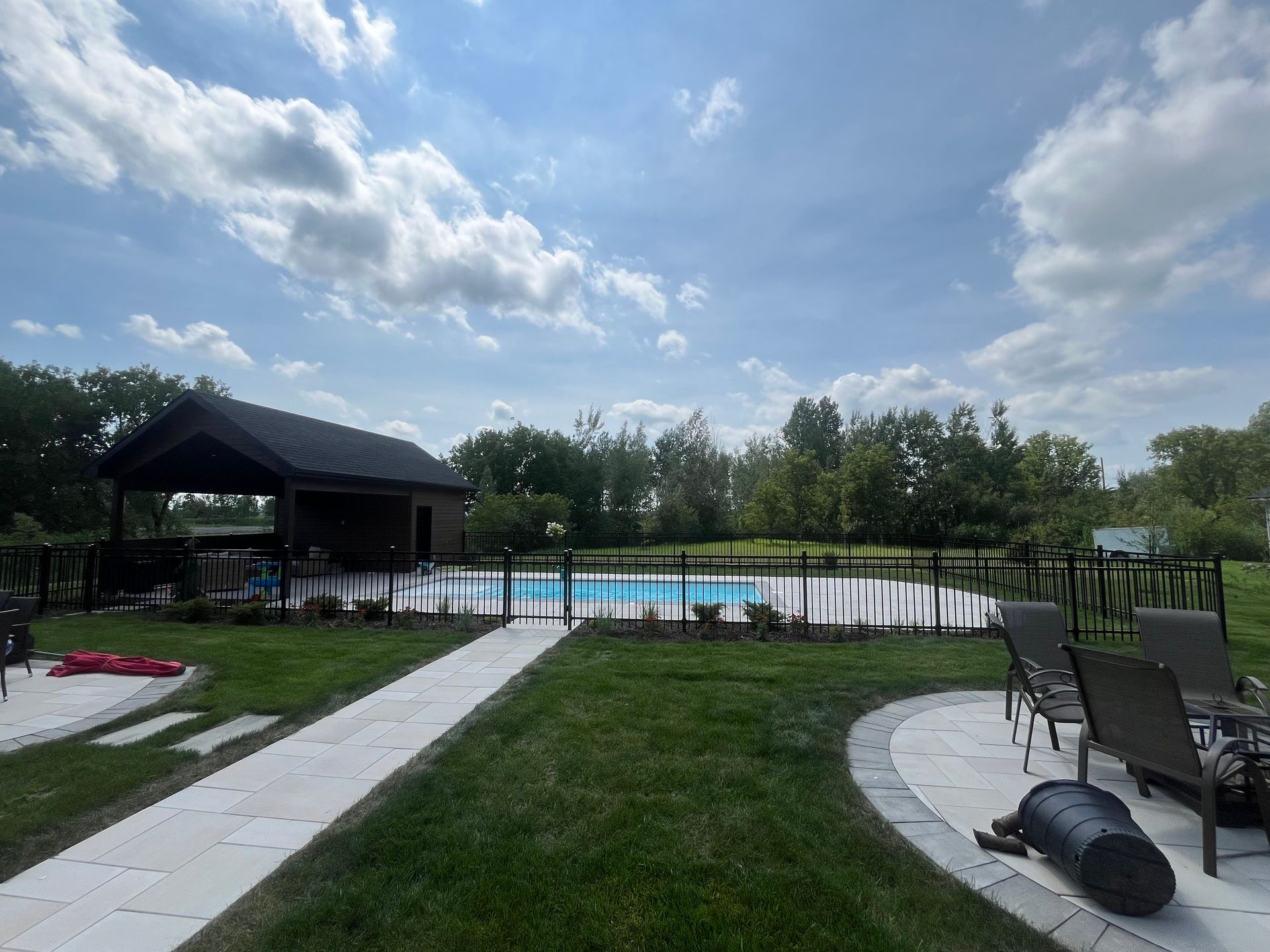 Une grande cour arrière avec une piscine et un gazebo.