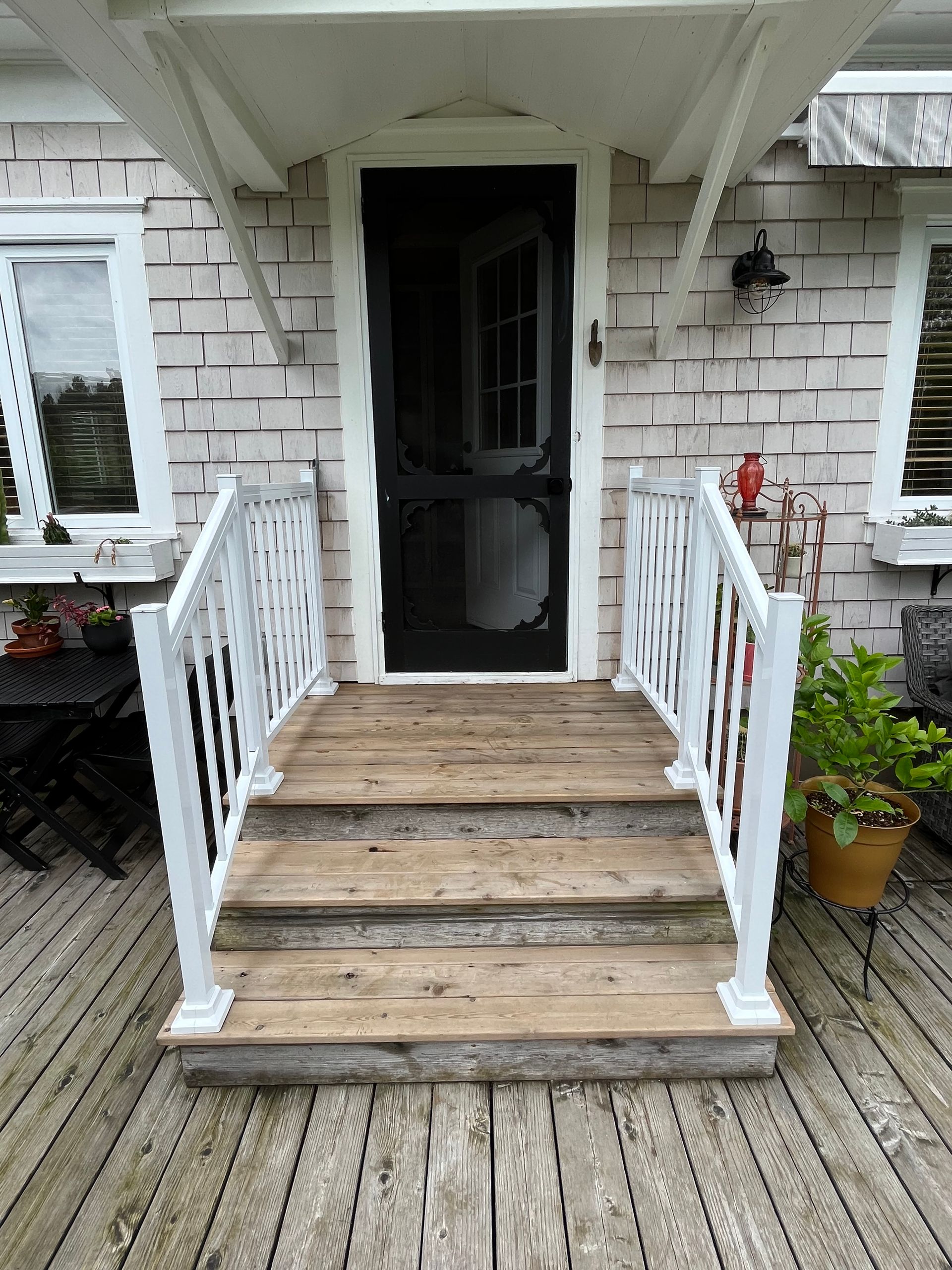 Un porche en bois avec des escaliers menant à la porte d'entrée d'une maison.