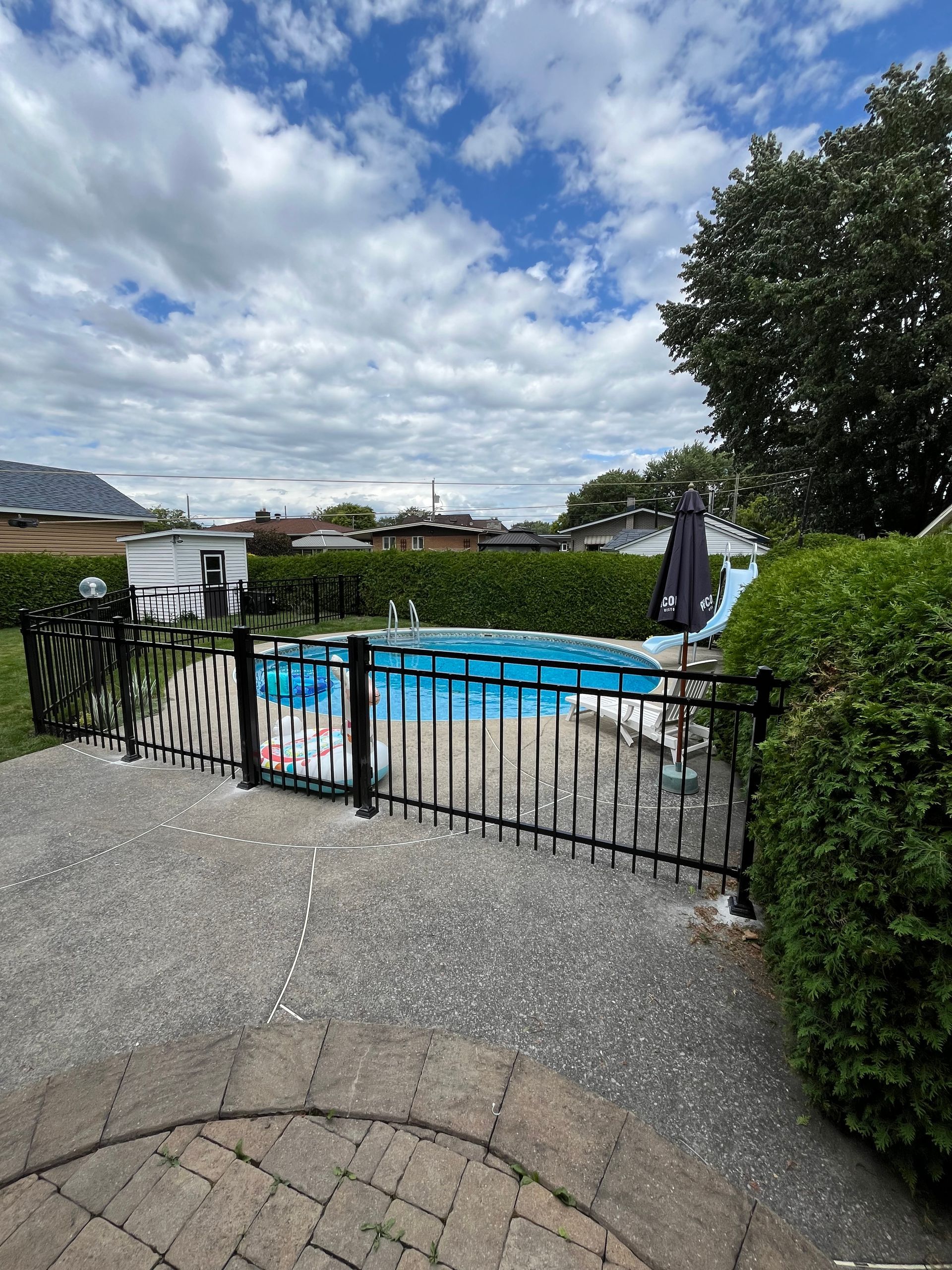Une clôture entoure une piscine dans une cour arrière.