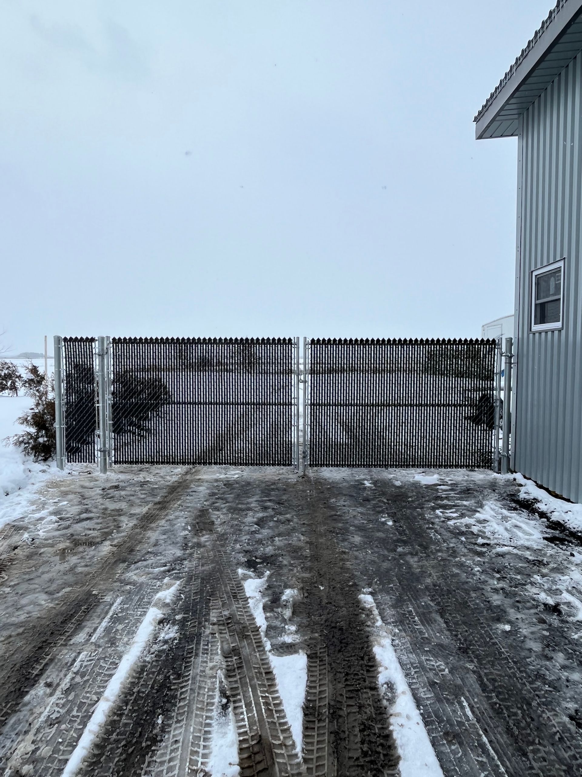 Une route enneigée avec une clôture au milieu.