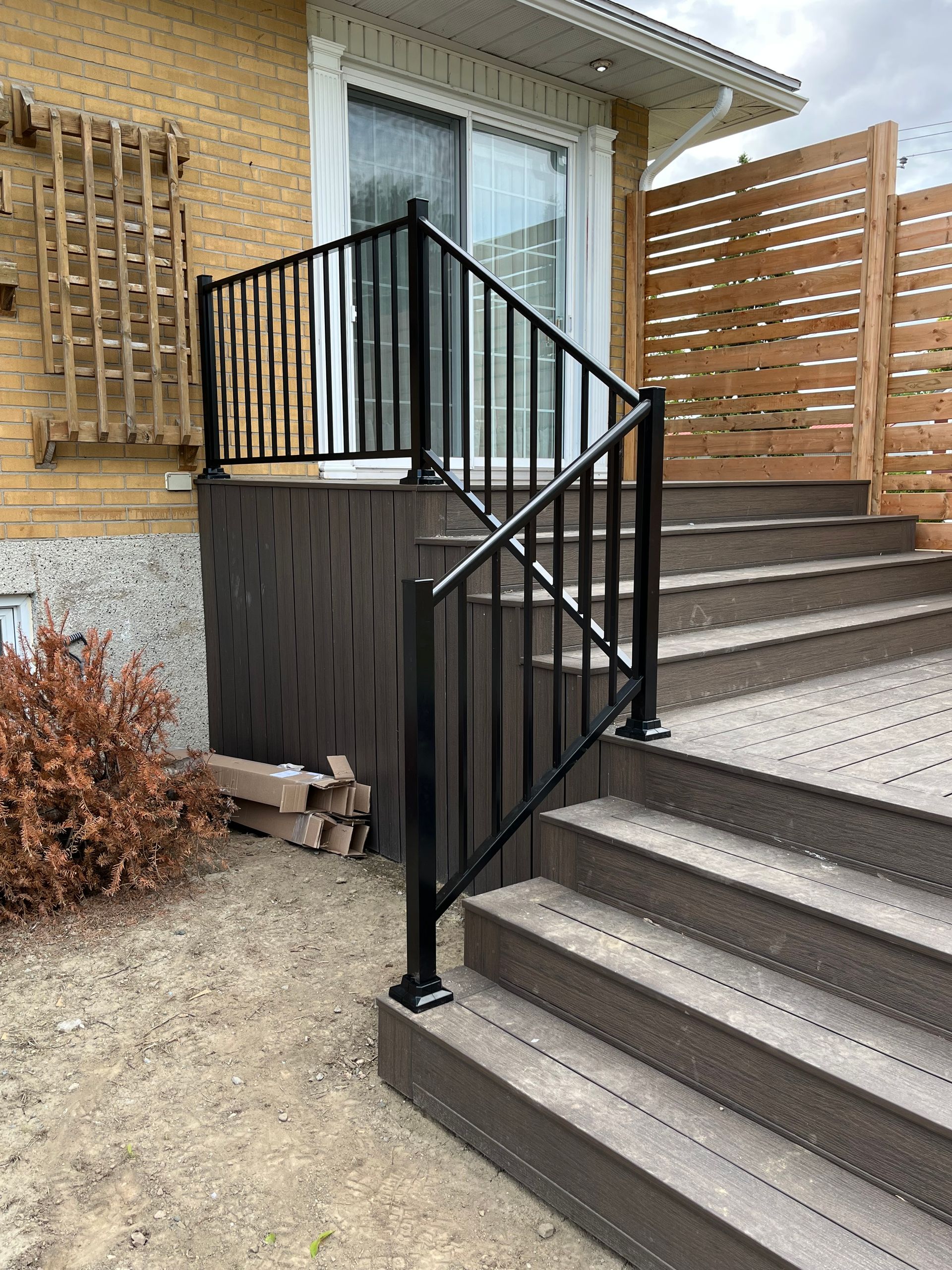 Une terrasse avec des escaliers et une balustrade devant une maison.