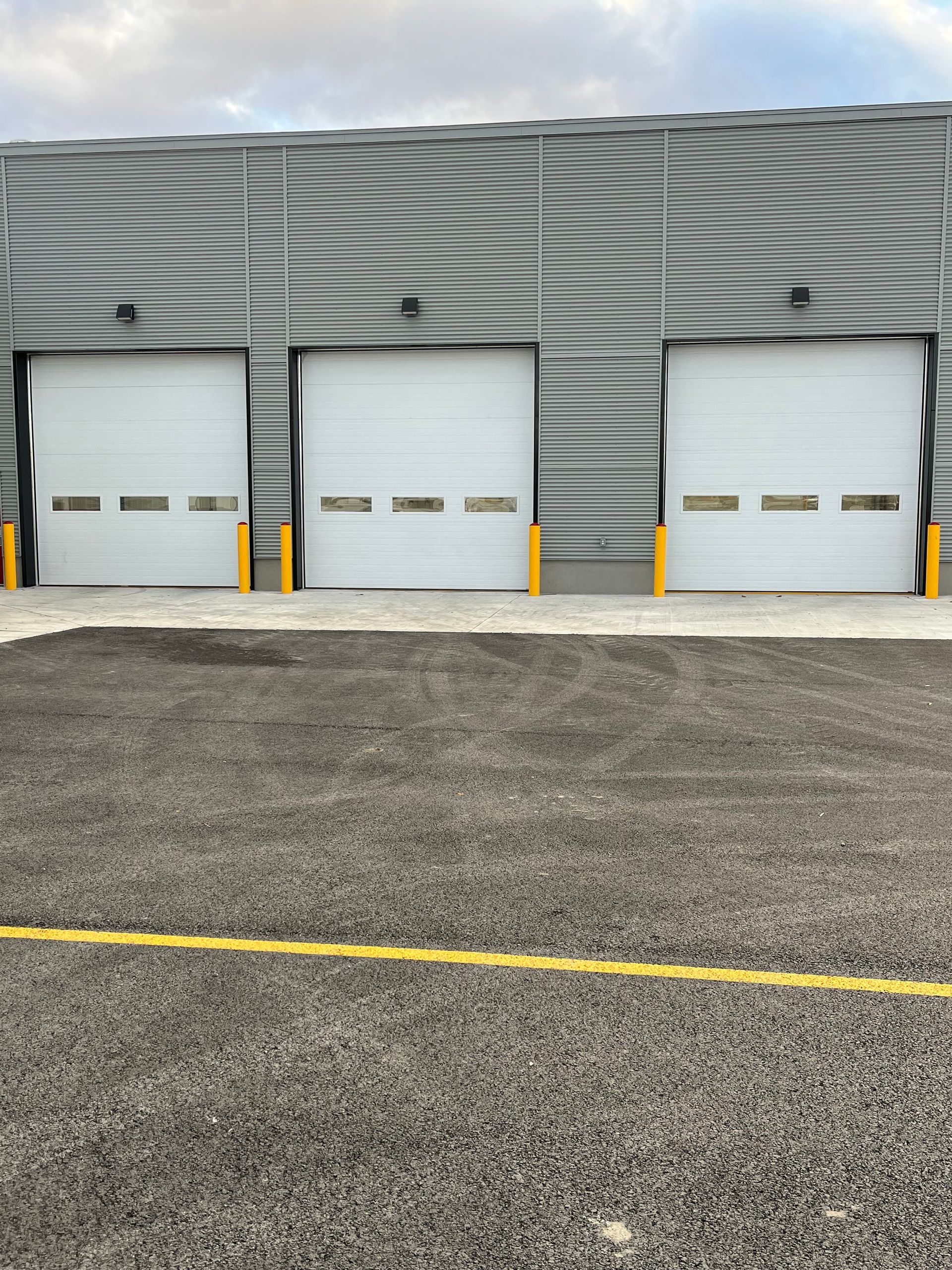 Une rangée de portes de garage blanches est alignée devant un bâtiment